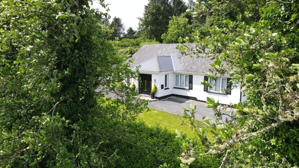 a white house in the middle of a forest at Kiltumper Lodge in Kilmihil