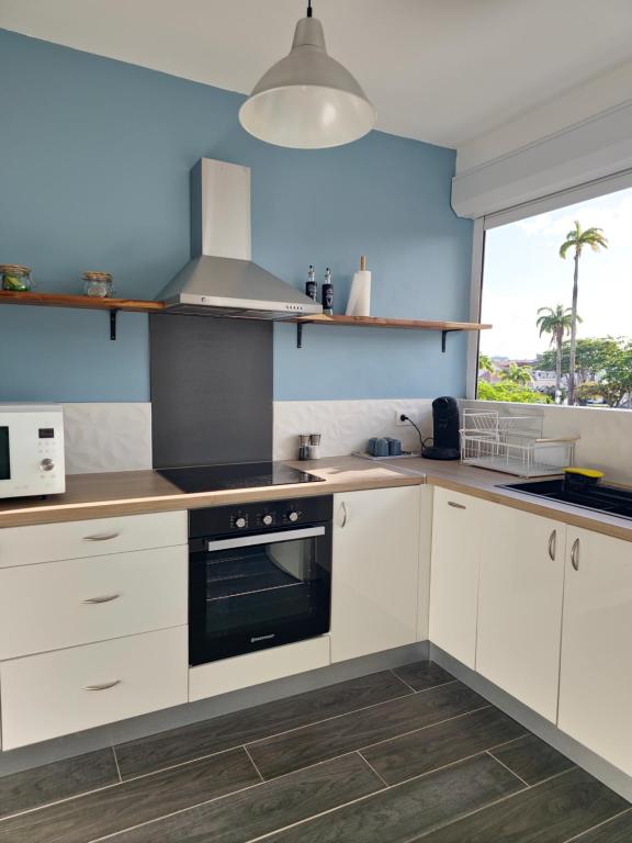 a kitchen with white cabinets and a large window at Amandine - Vue mer Pointe-à-Pitre in Pointe-à-Pitre