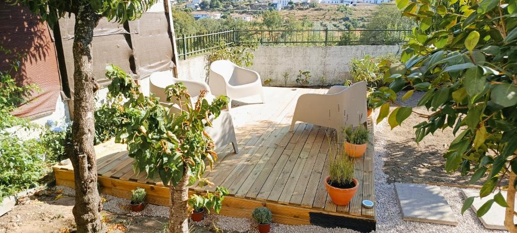 a patio with white chairs and potted plants at Cantinho da Saudade in Góis
