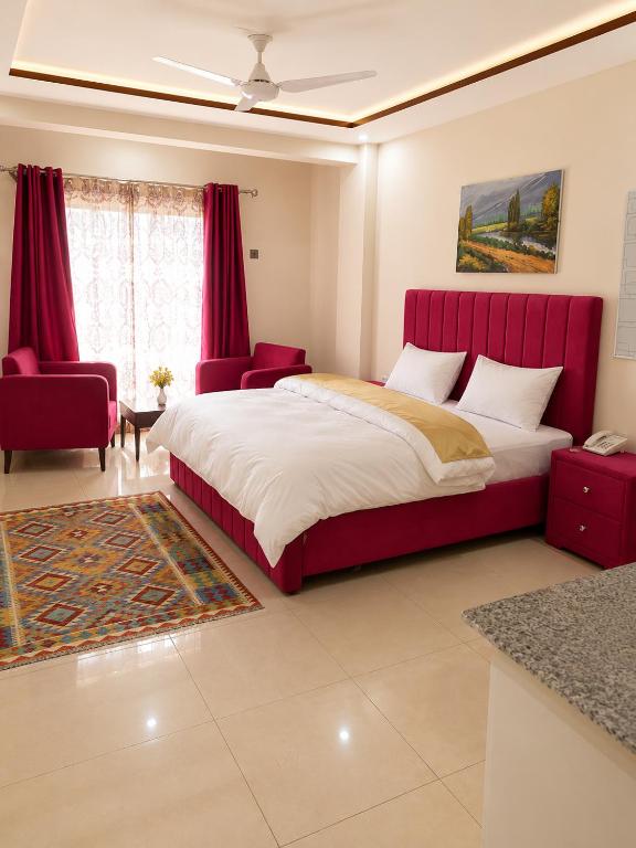 a bedroom with a large bed and a red headboard at We Hotels Islamabad Airport in Islamabad