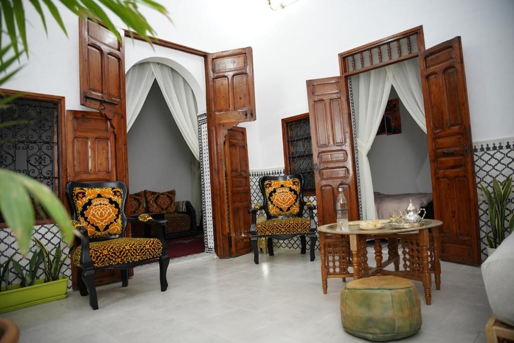 a living room with wooden doors and chairs and a table at Dar Mhani in Salé