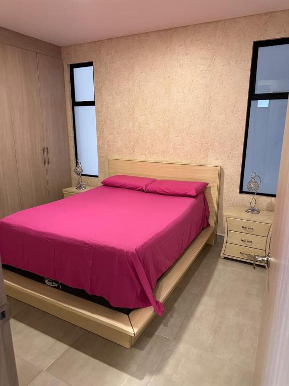 a bedroom with a pink bed with two windows at Cocora Stay in Armenia