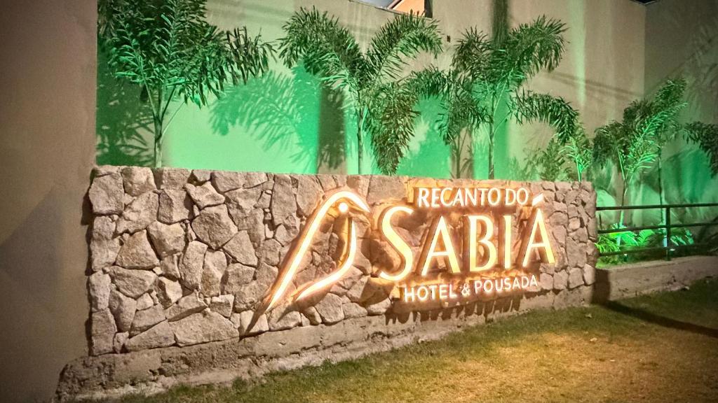 a neon sign on a stone wall in front of a building at Hotel & Pousada Recanto do Sabiá in Pirapora