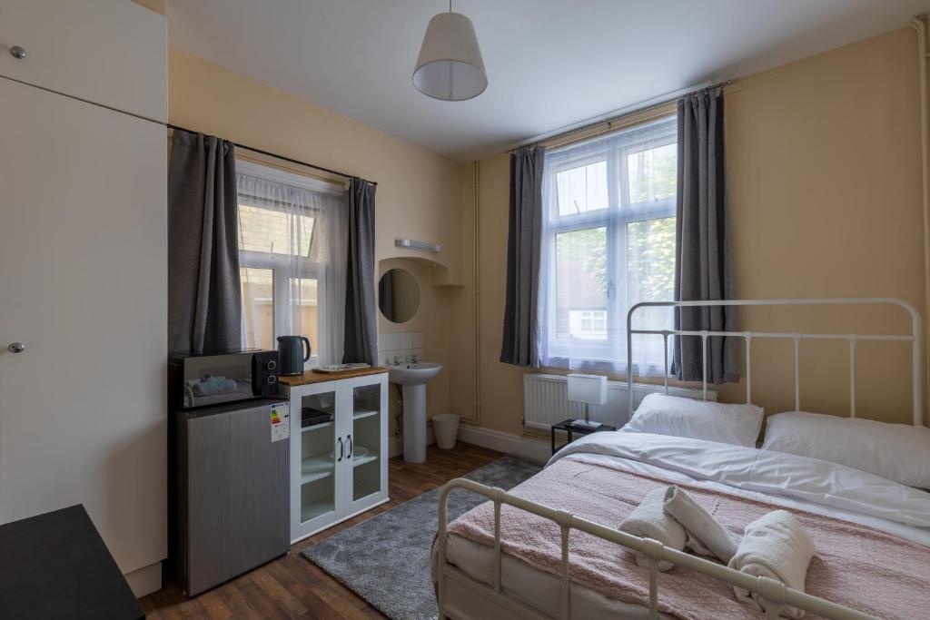 a small bedroom with a bed and a sink and window at Clare - Double Room 20 mins walk to centre -Kitchenette Smart TV Shared bathroom in Chesterton