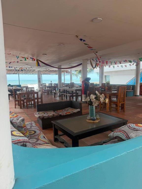 a living room with tables and chairs and the ocean at hostal EMBAMAR in Palomino