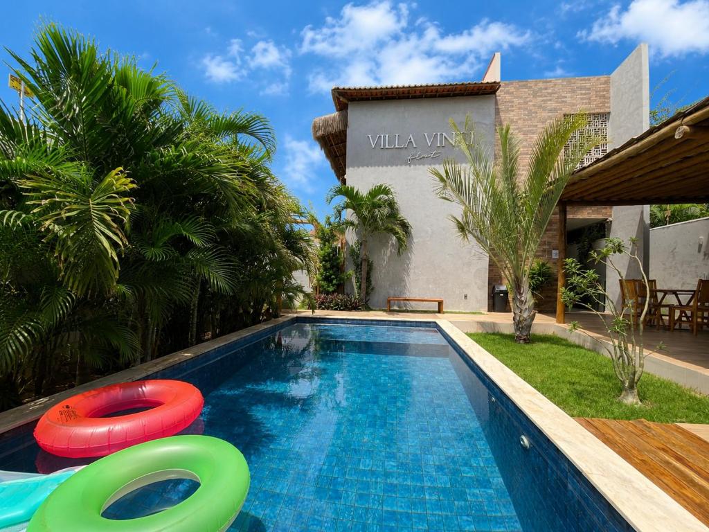 a swimming pool with two frisbees next to a house at Villa Vinci Flat in São Miguel do Gostoso