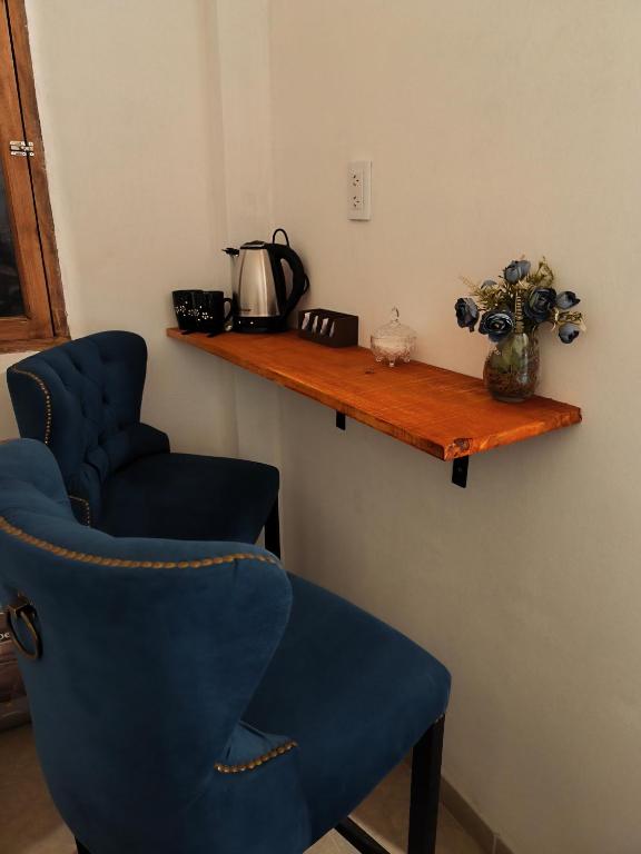 a room with two blue chairs and a wooden shelf at Urku Runa in Humahuaca