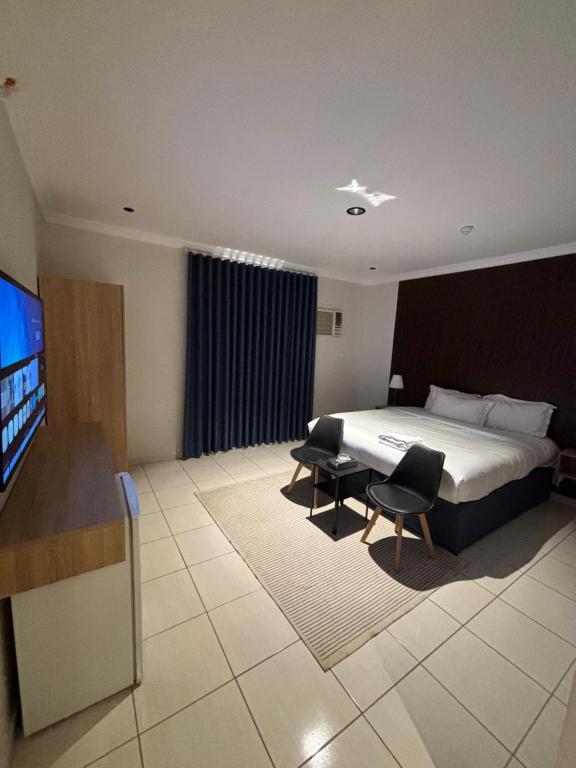 a hotel room with a bed and two chairs and a television at Alassaf 304 in Sīdī Ḩamzah