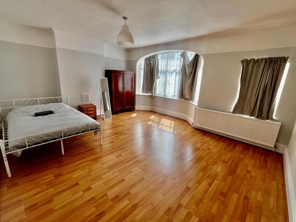 an empty room with a bed and a wooden floor at East Croydon Train Station in Croydon