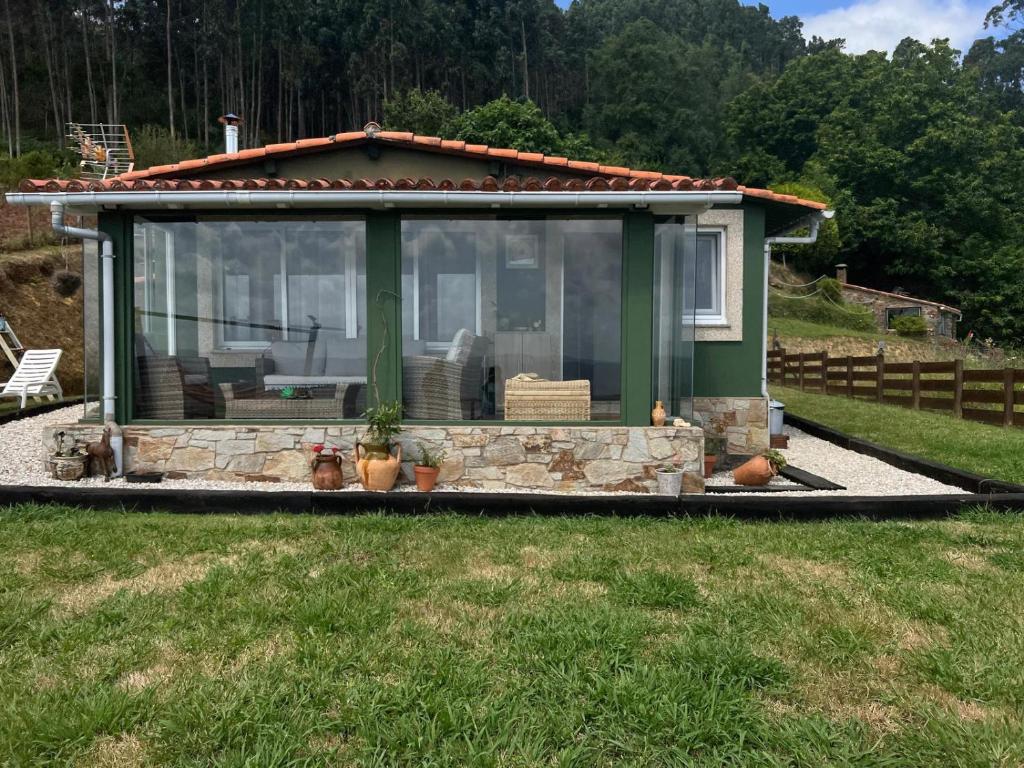 a small house with a large window on the grass at La Cabaña del aviador in Feás