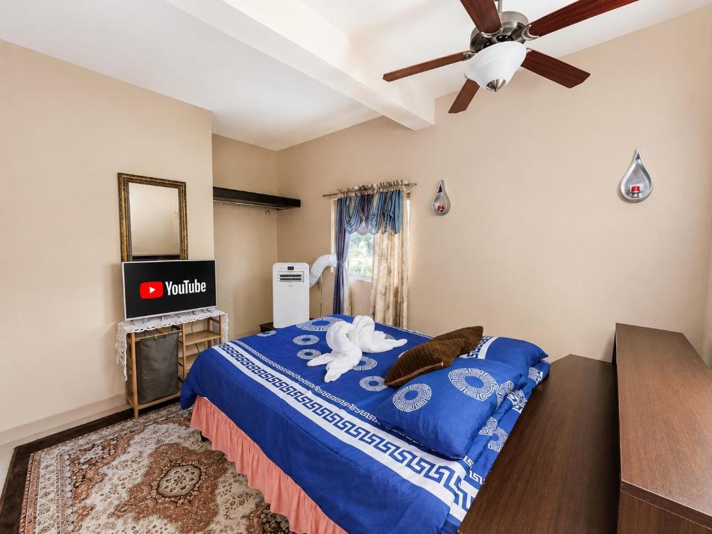 a bedroom with a blue bed with a ceiling fan at Serenity Escape, Cozy Stay w Secure Parking in Runaway Bay