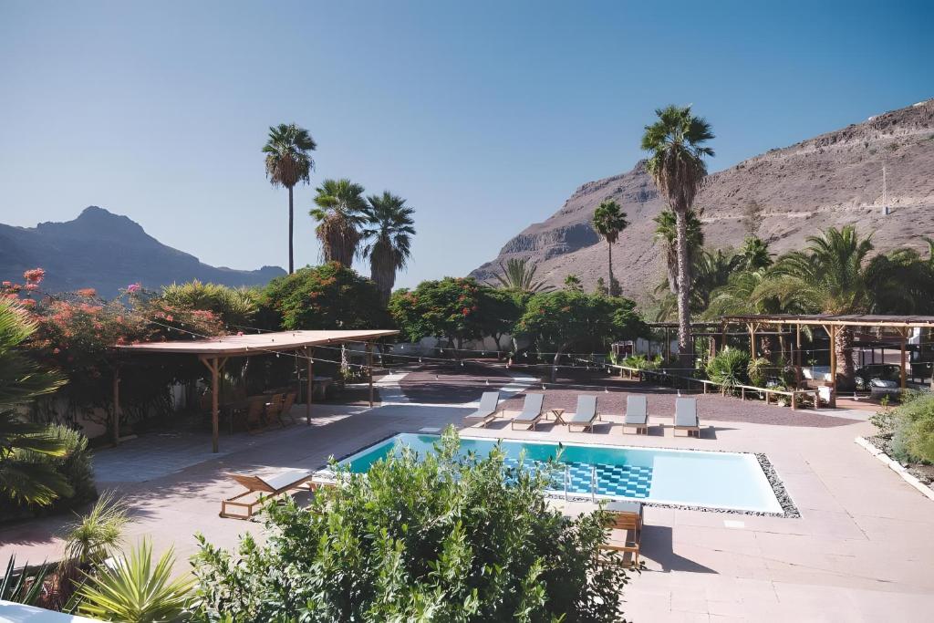 a resort with a pool and palm trees and a mountain at Finca rural Los Tanquillos in San Bartolomé
