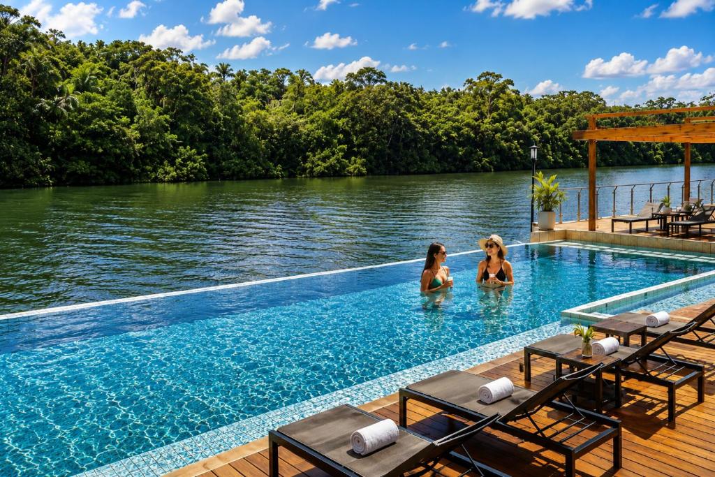 two women in a swimming pool next to a body of water at Grand Resort & Residences in Belize City