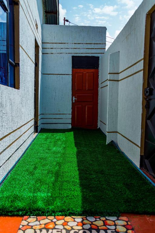 a building with a red door and green grass at The new home in Moshi