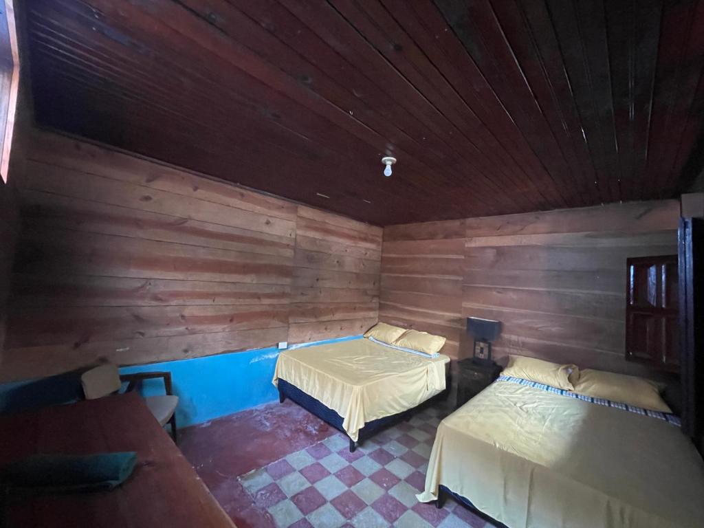a room with two beds in a wooden room at Hotel bar y restaurante Millenium Lanquin in Lanquín