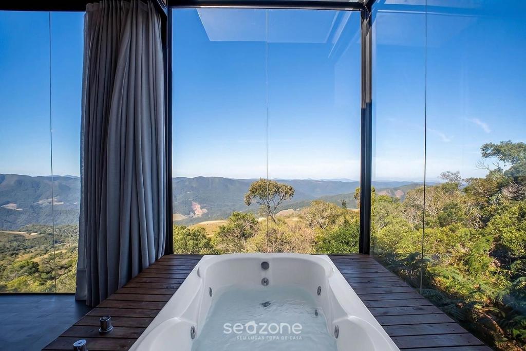 a bath tub in a room with a large window at Charming chalet with fireplace and hot tub! VST045 in Annitapolis