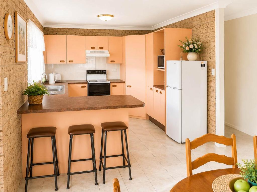 a kitchen with a white refrigerator and some chairs at Seascape Carroll Avenue - close to Mollymook Beach in Mollymook