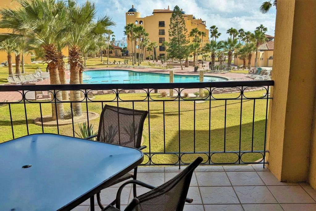 a balcony with a table and chairs and a pool at Princesa de Penasco B208 - Family Beach Getaway in Puerto Peñasco