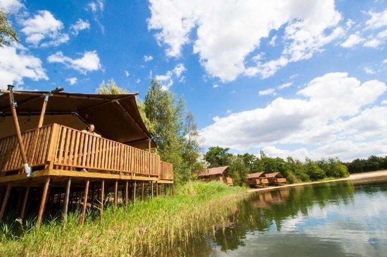 a building with a deck next to a river at Waterlodge 8 persons #WL02 in Maasbree