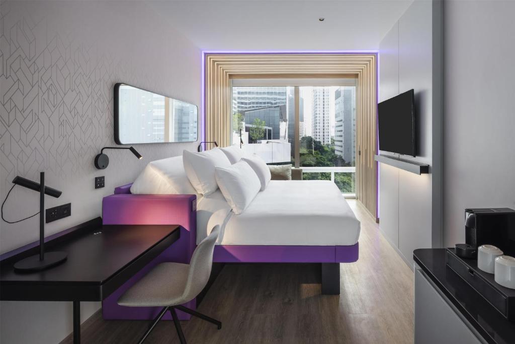 a hotel room with a bed and a desk and a window at YOTEL Bangkok Sukhumvit in Ban Nong Chaeng