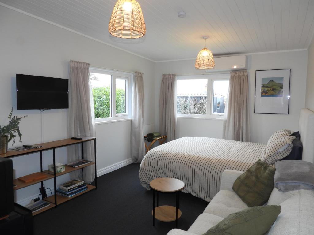 a bedroom with a bed and a couch and a tv at Stirling St Surf Villa in Dunedin