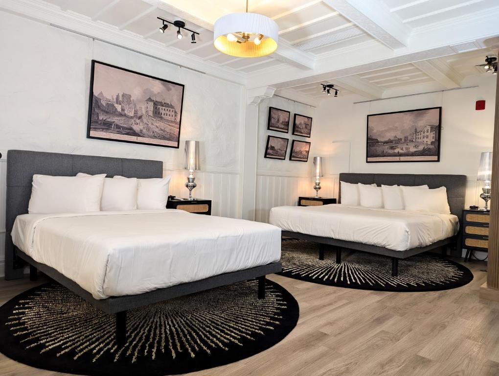 two beds in a bedroom with white walls at Hotel Manoir Morgan in Quebec City
