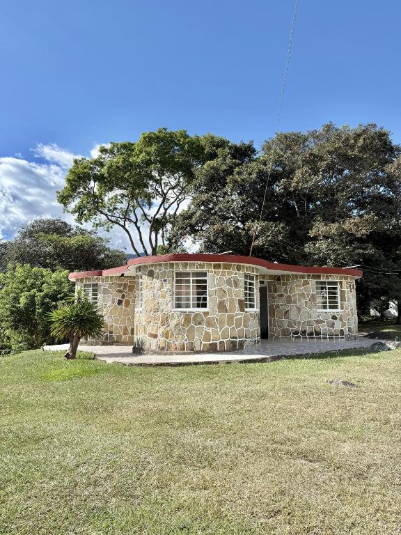 a stone house in a field with a tree at Cabañas El Itali in Fusagasuga