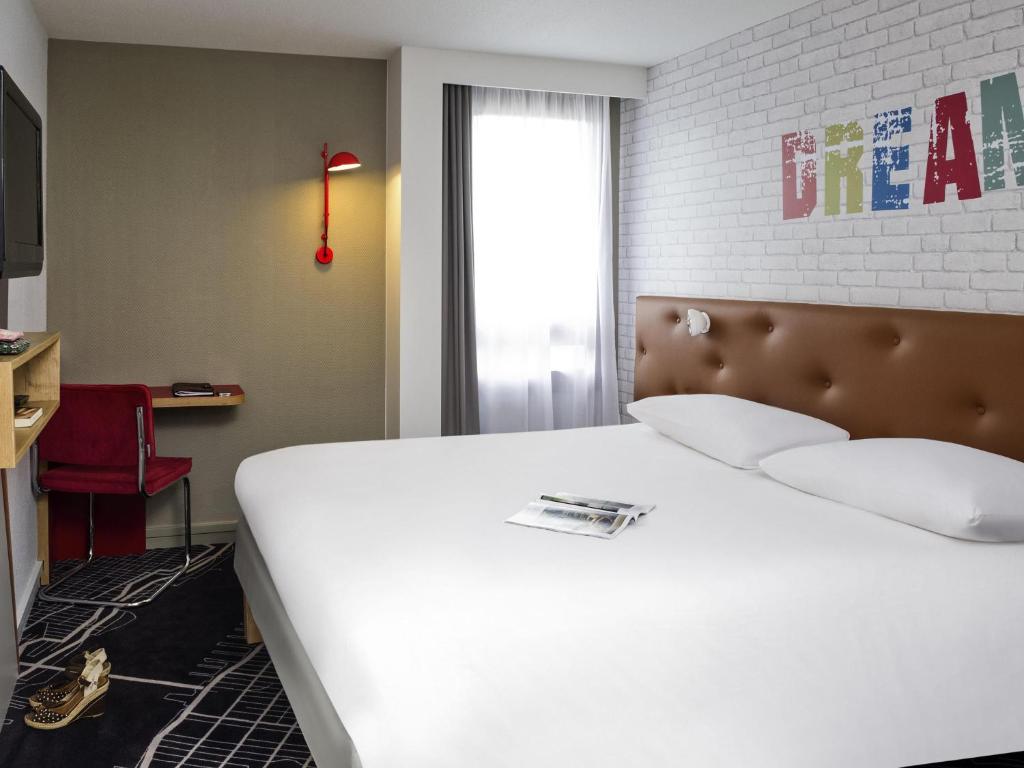 a bedroom with a large white bed and a window at ibis Styles Chartres Métropole in Chartres