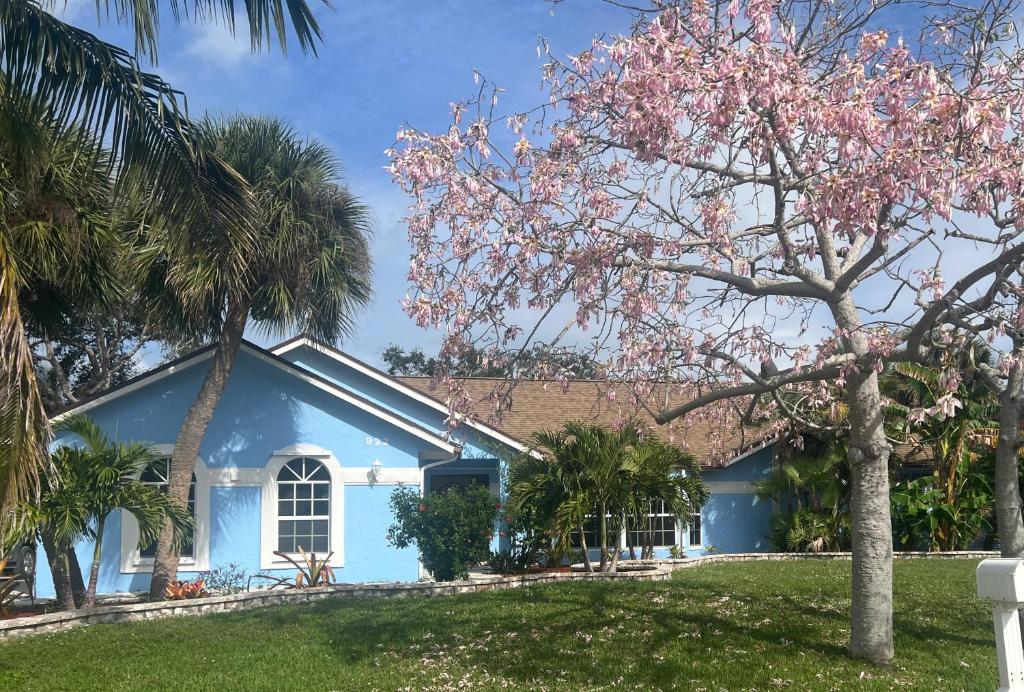 a blue house with palm trees in front of it at Hutchinson River House in Fort Pierce