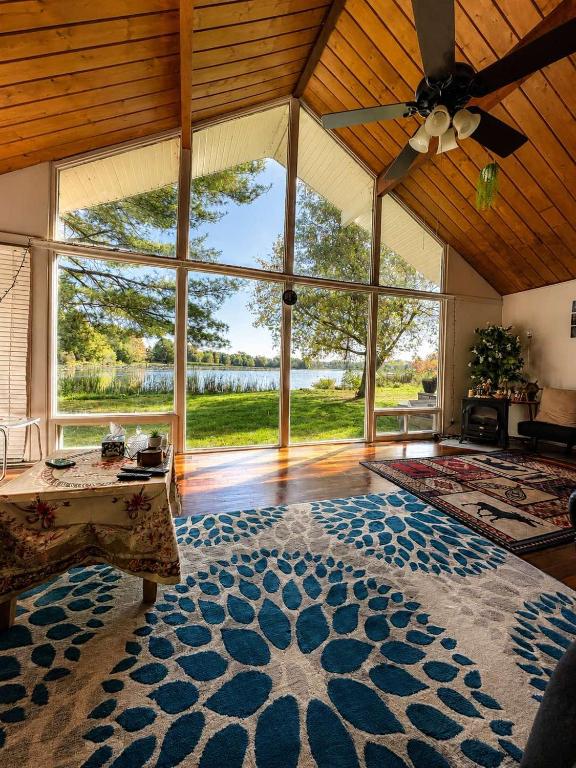 a large living room with a ceiling fan and a large window at DREAM LAND Lake Front CHALET, HOT TUB in Huntingdon