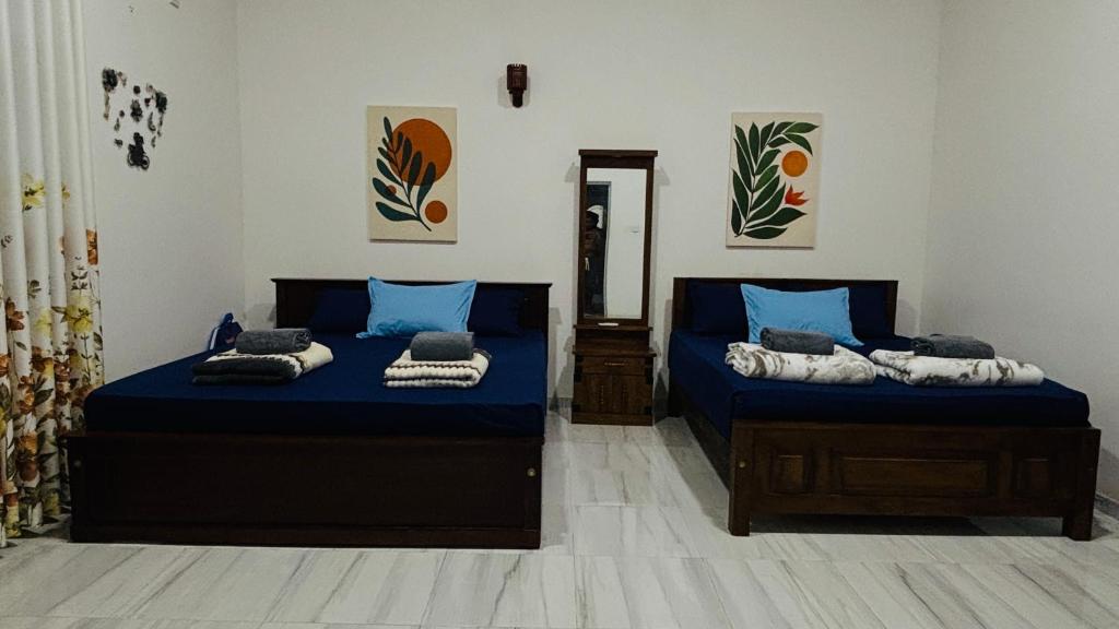 two beds with blue sheets in a room at Elisha Place Hiriketiya in Dickwella