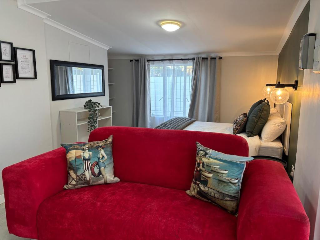 a living room with a red couch and a bed at The Red Couch Accommodation in Tsumeb