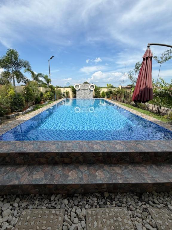 a swimming pool with an umbrella in a yard at BalaiBesa Transient House in Lingayen