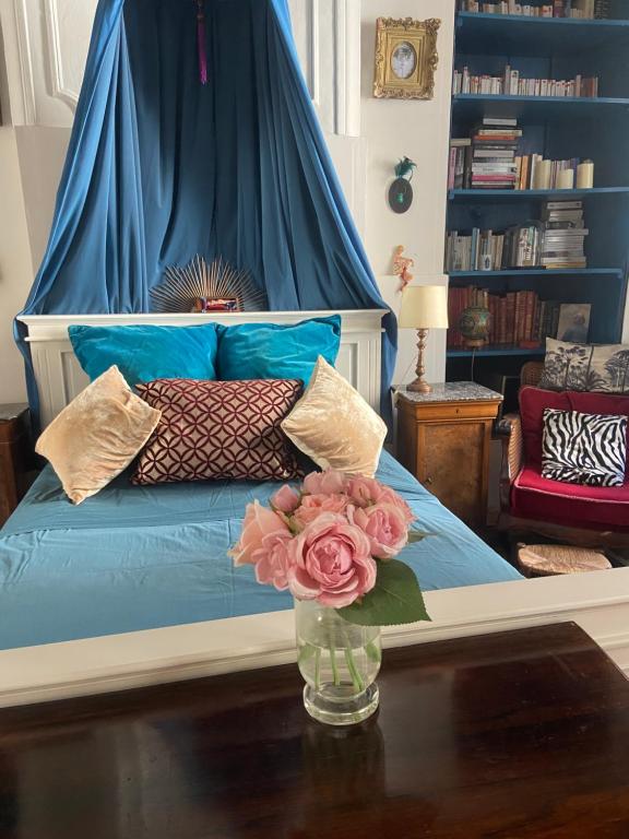 a bedroom with a bed with a vase of flowers on a table at Le Boudoir d'artiste in Semur-en-Auxois
