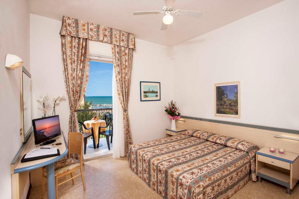 カットーリカにあるHotel Brigのベッド、デスク、テレビが備わるホテルルームです。