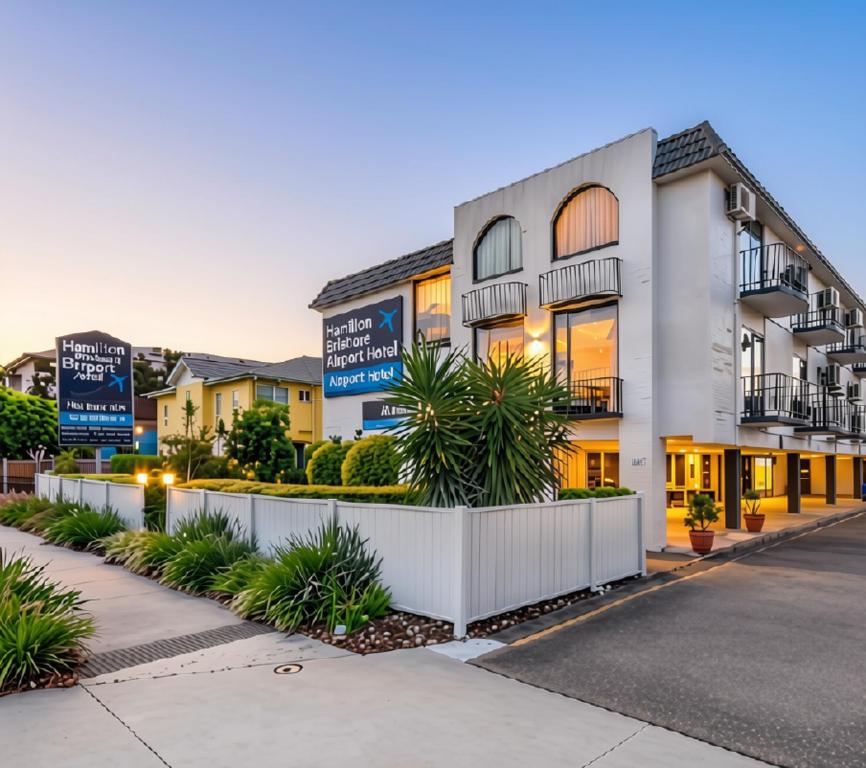 a white building with signs in front of it at Hamilton Brisbane Airport Hotel in Brisbane