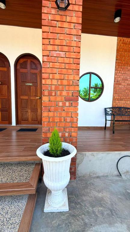 a white vase with a plant in it on a porch at Bunohan Villa Roomstay in Tumpat