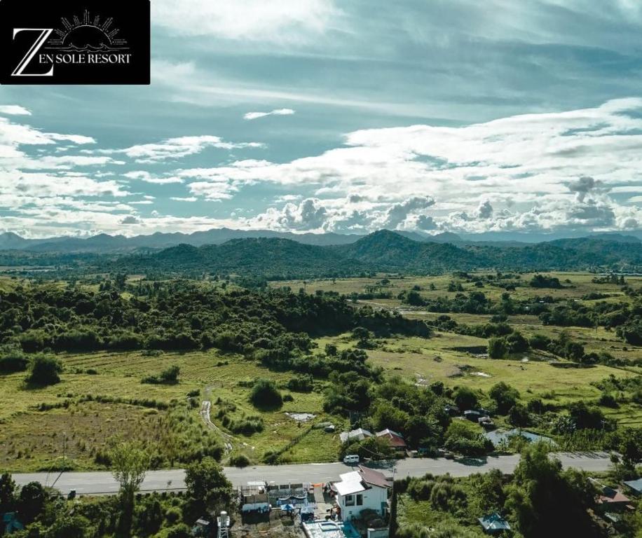 an aerial view of a field with mountains in the distance at Zensole Resort in Tarlac