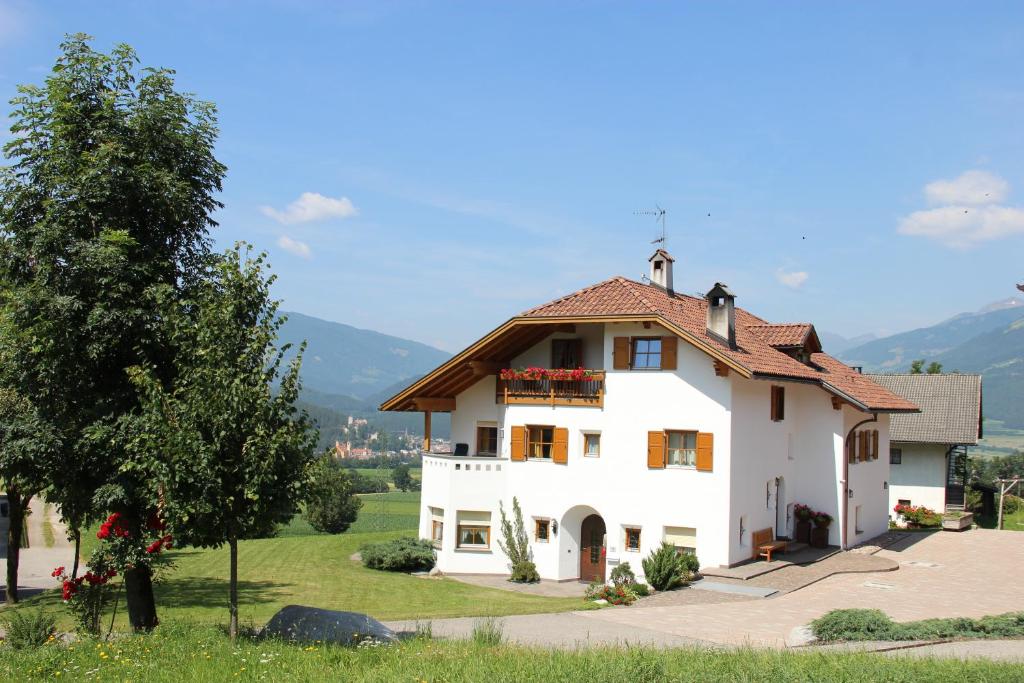 a white house with a red roof and a tree at Appartement Huber in Brunico