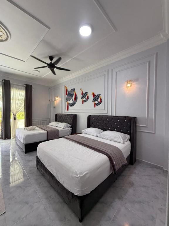 a bedroom with two beds and a ceiling fan at Bunohan Villa Homestay in Tumpat