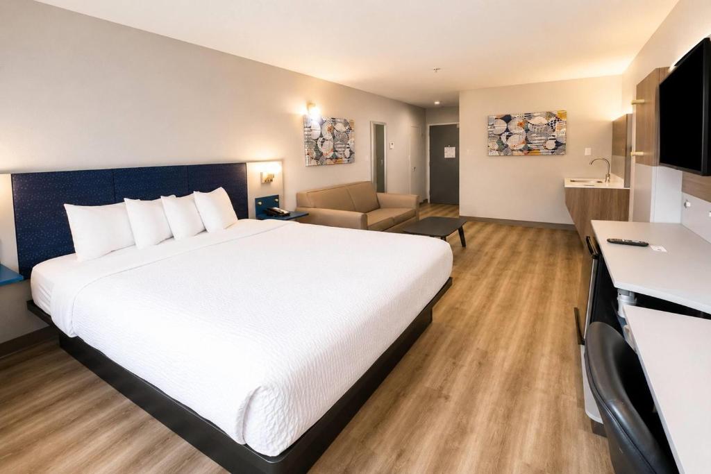 a hotel room with a large white bed and a couch at Microtel Inn & Suites by Wyndham Macon in Wesleyan Hills