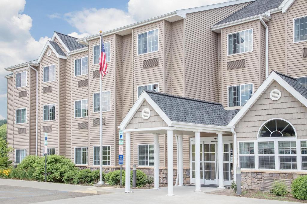 a large building with a flag in front of it at Microtel Inn & Suites Mansfield PA in Mansfield