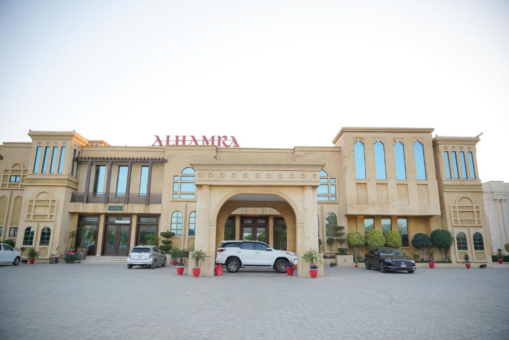 a building with cars parked in front of it at Alhamra Hotel in Mardan