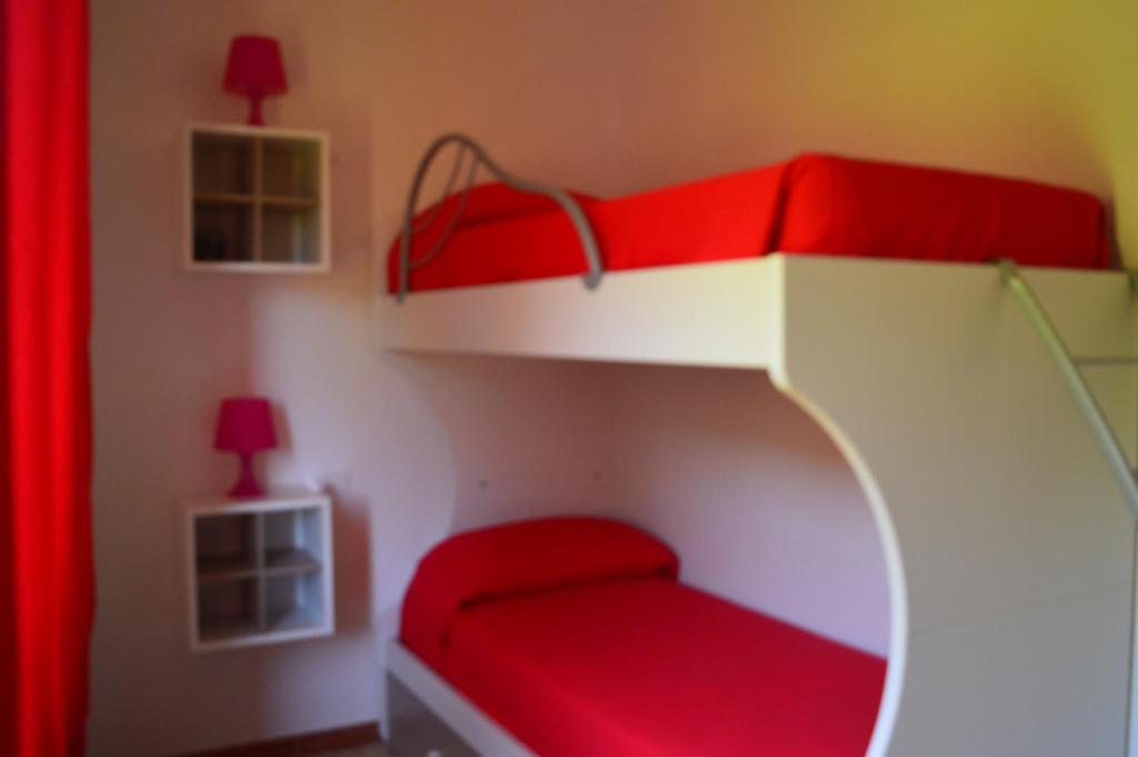 Casa Vacanza La Zanca في Zanca: غرفة نوم مع سرير بطابقين احمر وبيضاء