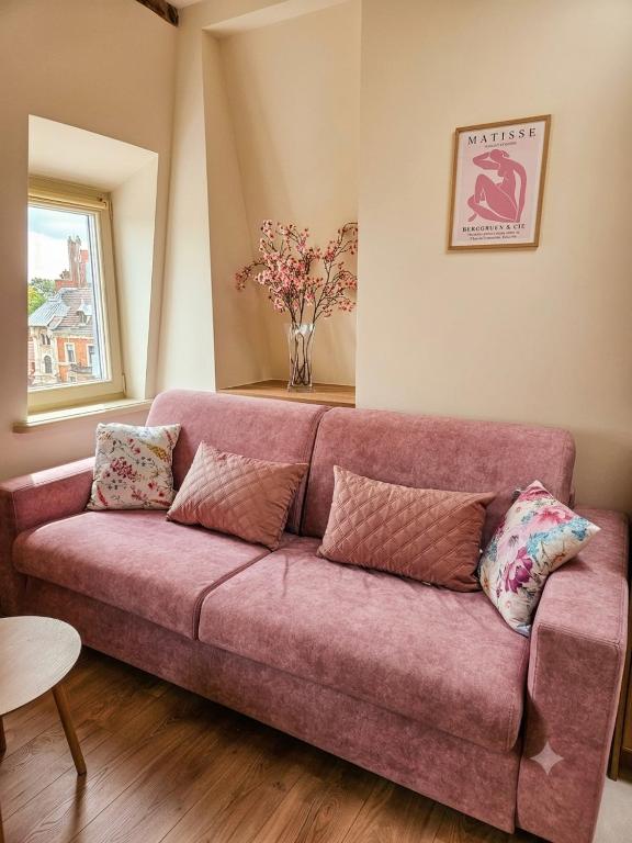a pink couch in a living room with a vase of flowers at Rosette Rose AC Progres in Toruń