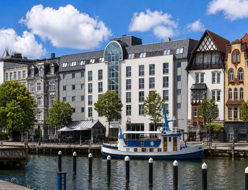 a boat in the water in front of a building at Sunday Hotel Flensburg in Flensburg