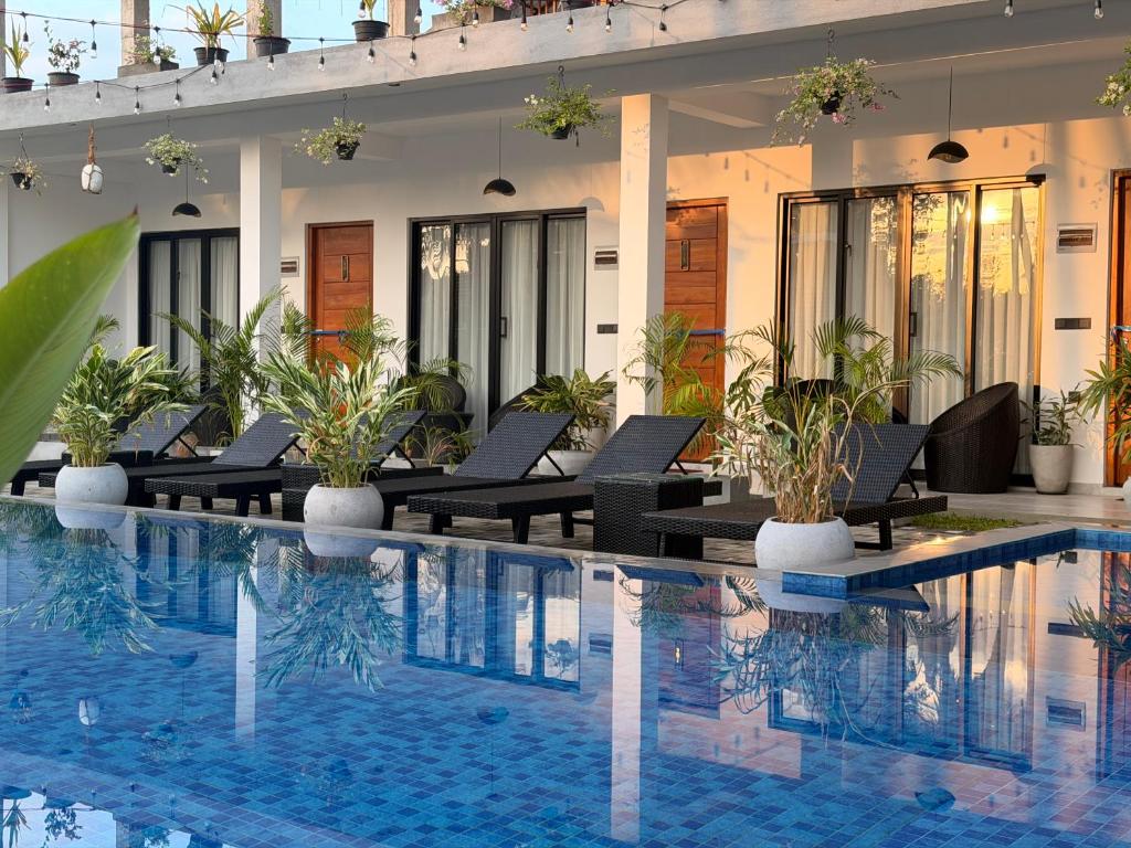 a pool at a hotel with chairs and plants at Lumora Fresh Wave Arugambay in Arugam Bay