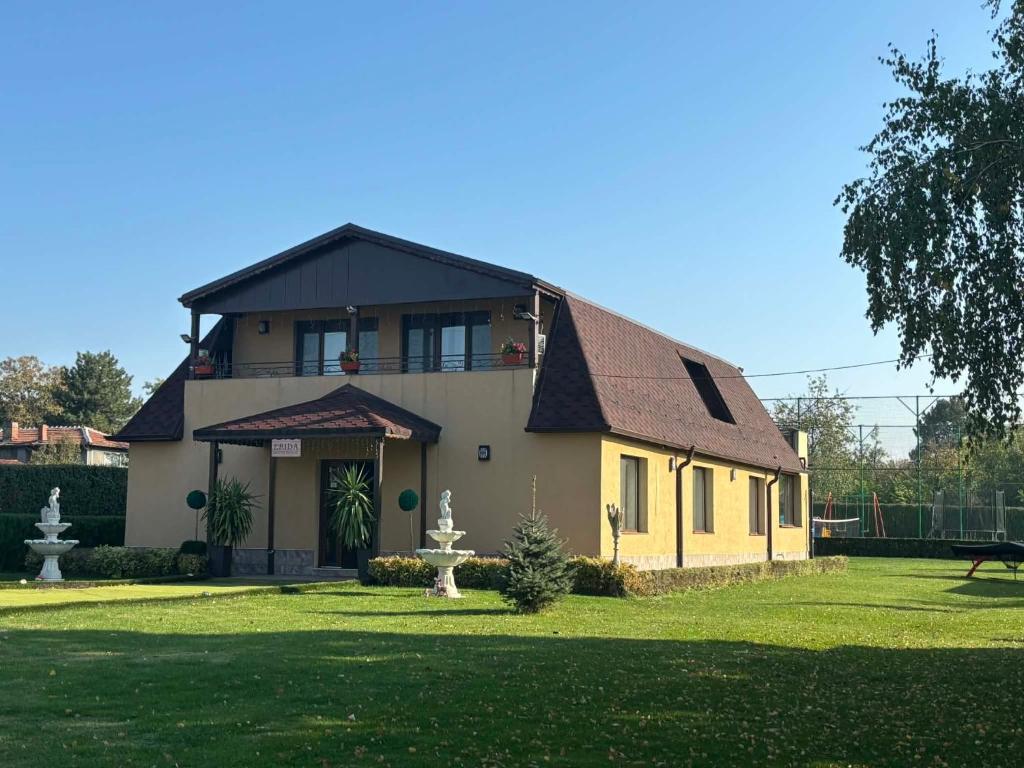 a yellow house with a black roof on a yard at Erida Guest House - къща за гости до Русе in Trastenik
