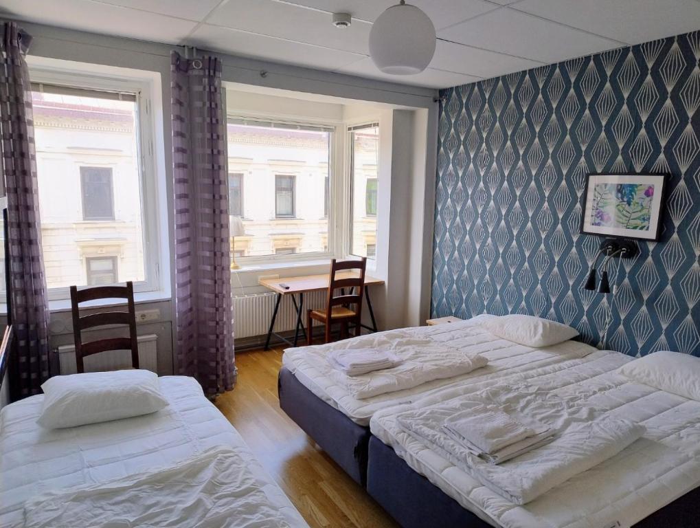 a bedroom with two beds and a table with chairs at Avenyn Hostel, former Le Mat in Gothenburg