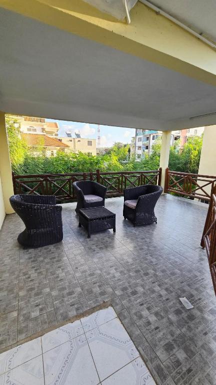 a patio with chairs and tables on a balcony at Logement des palmiers in Flic-en-Flac